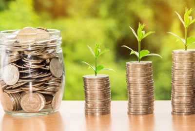plants growing on coins next to a jar of money