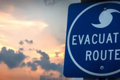 Blue evacuation route road sign with sunset in background.