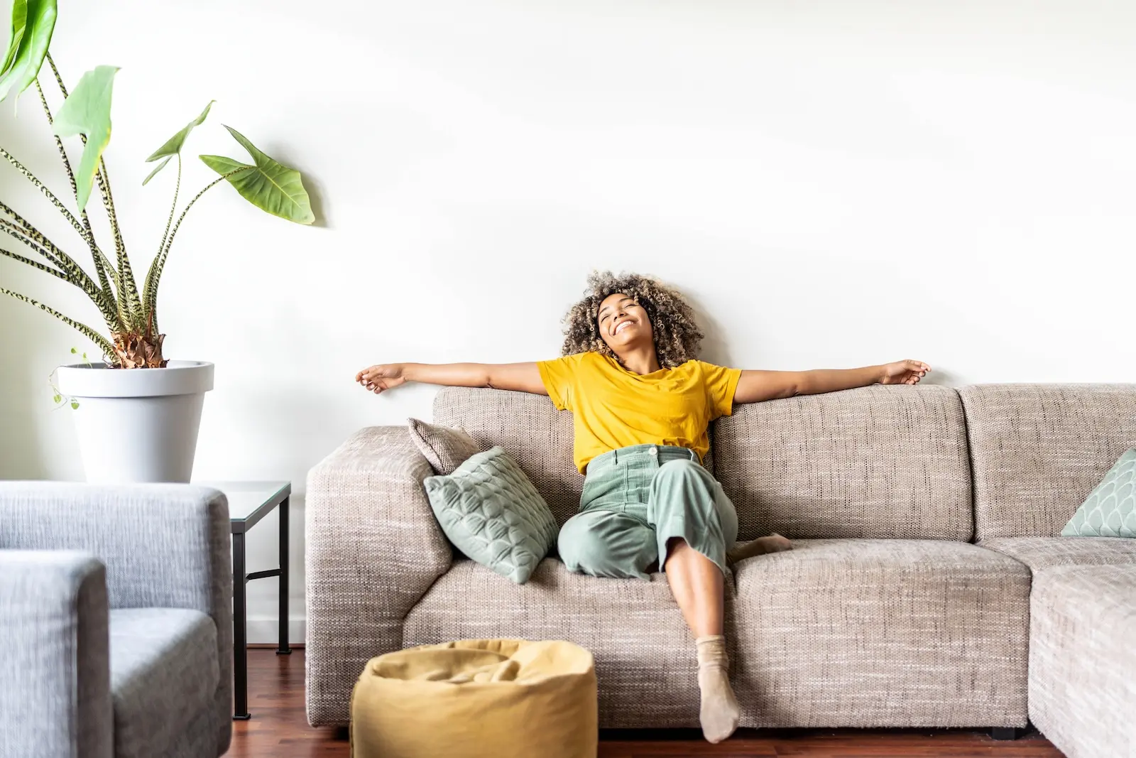 Woman sitting on couch in Lafayette home with arms spread out.