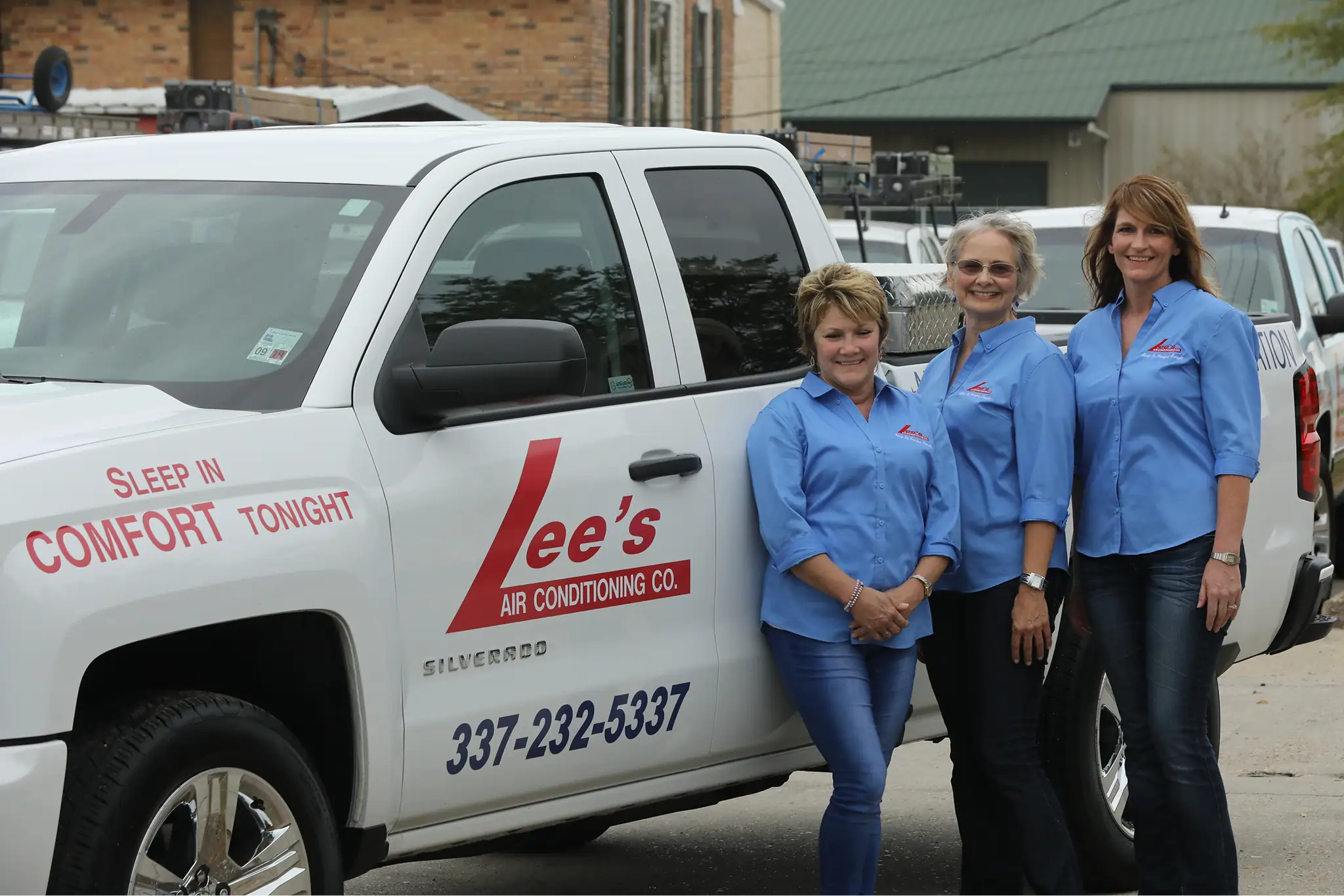 Three Lee’s AC employees standing next to one another, leaning against a service truck.