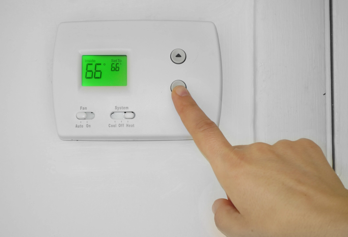 Person setting thermostat to heat and lowering the temperature.