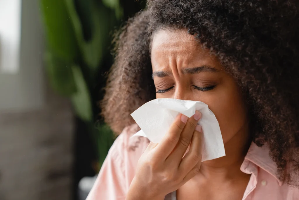 Woman sneezing due to seasonal allergies in Acadiana. 