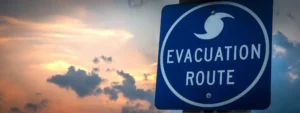 Blue evacuation route road sign with sunset in background.