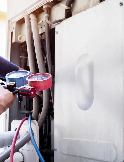 Repair technician using pressure gauge to troubleshoot a heat pump.