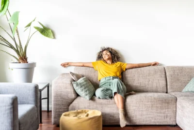 Woman sitting on couch in Lafayette home with arms spread out.