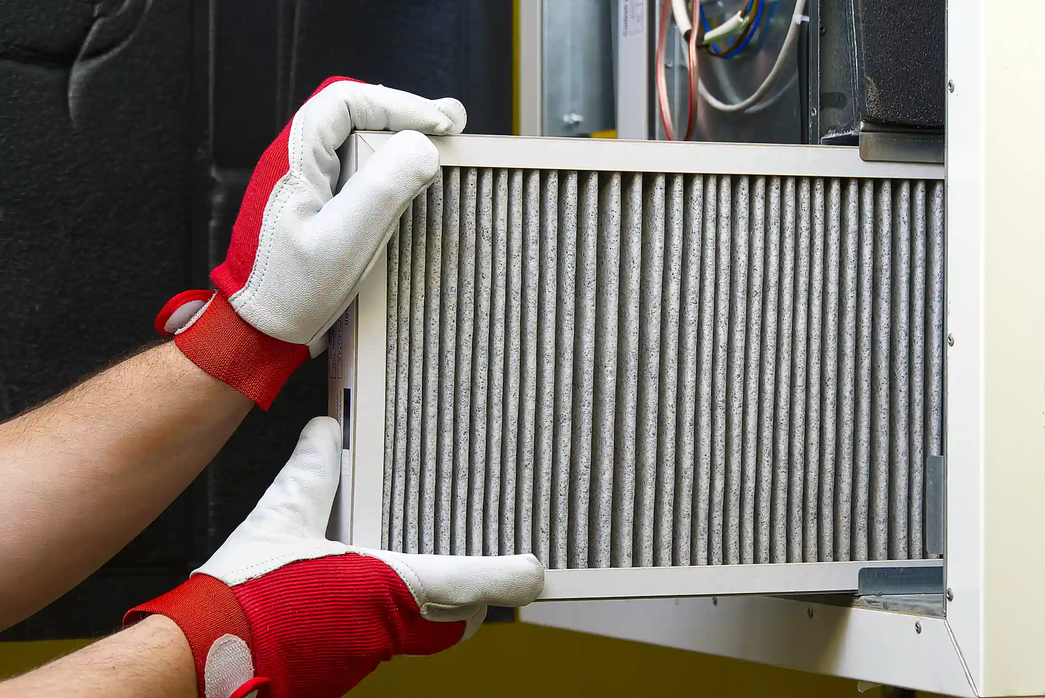 Person replacing an air filter inside HVAC unit for improved indoor air quality.